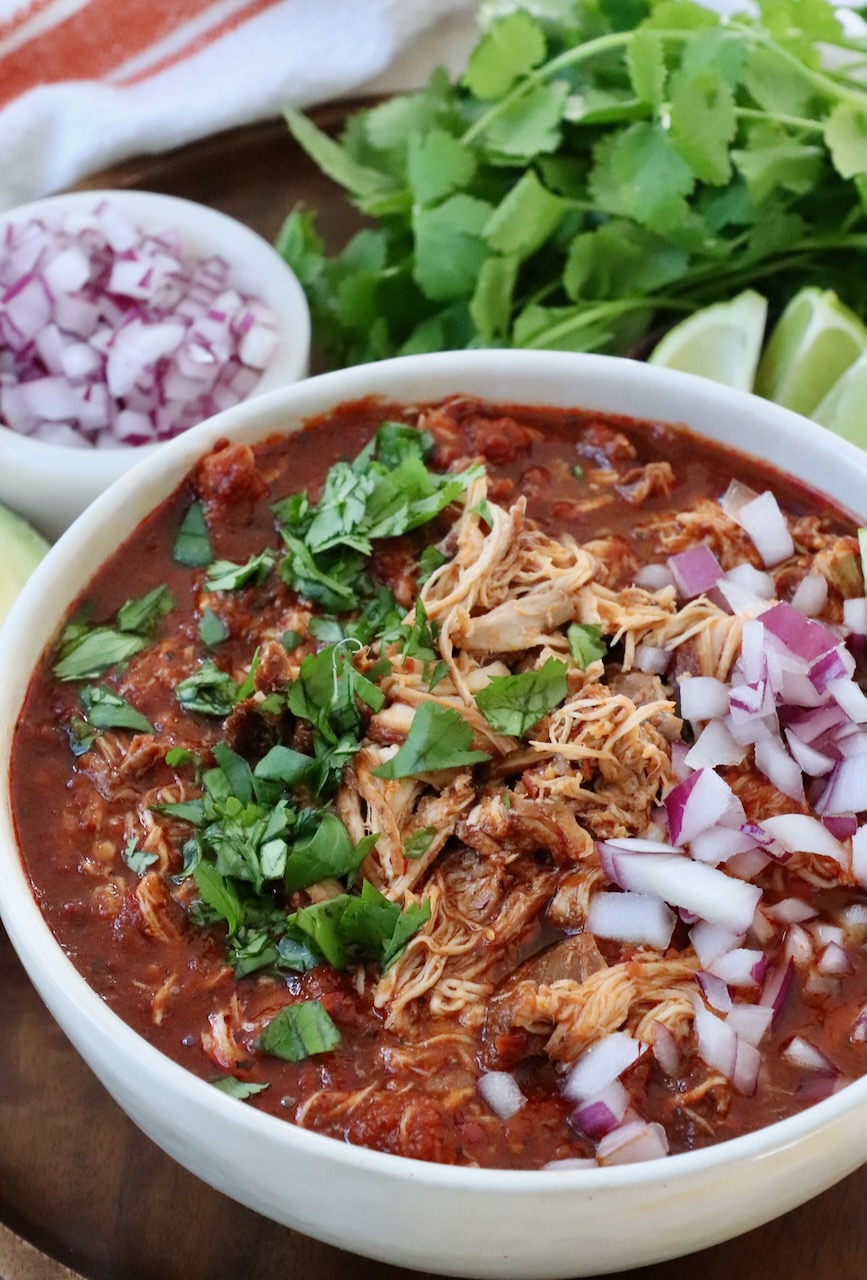 chicken birria in bowl topped with fresh cilantro and diced red onions