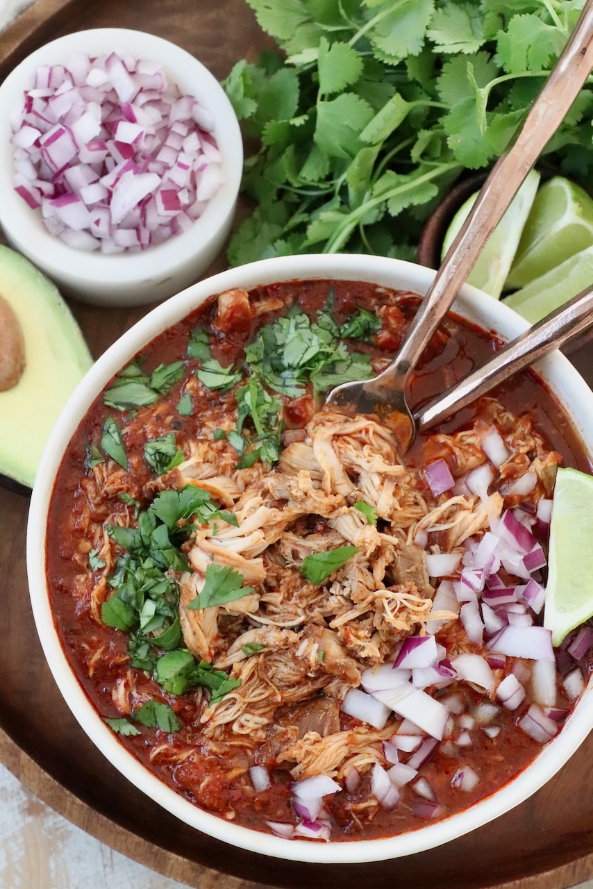shredded chicken in birria broth in bowl with forks