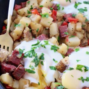corned beef hash in skillet with over easy eggs on top and fork on the side
