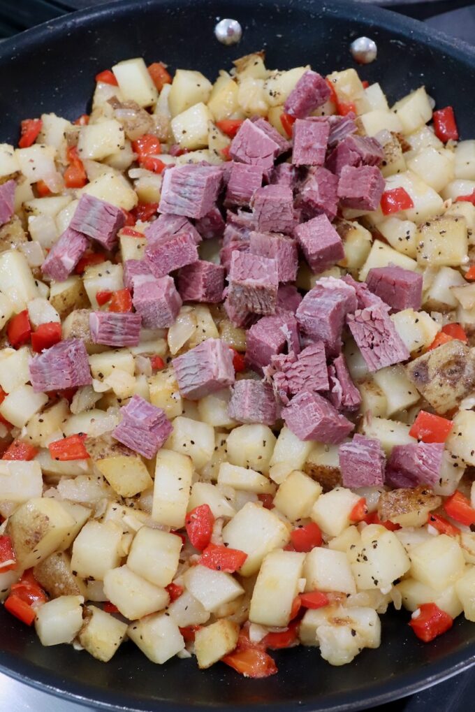 diced corned beef with diced potatoes, onions and peppers in a large skillet