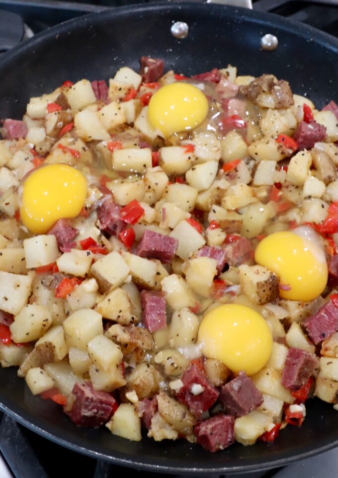 raw eggs, cracked on top of corned beef hash in a large skillet