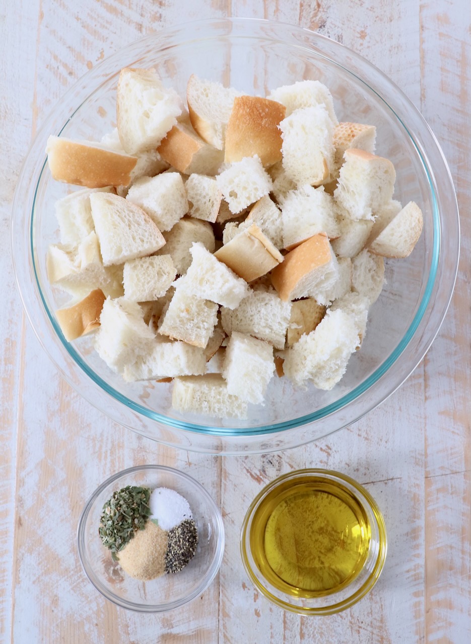 ingredients for homemade croutons on white wood board