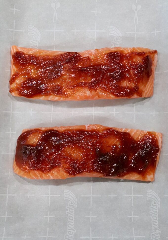 salmon filets on parchment lined baking sheet topped with miso glaze