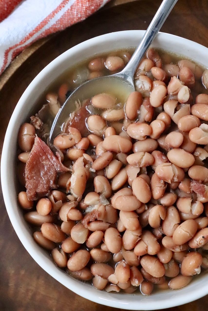 cooked pinto beans in bowl with spoon