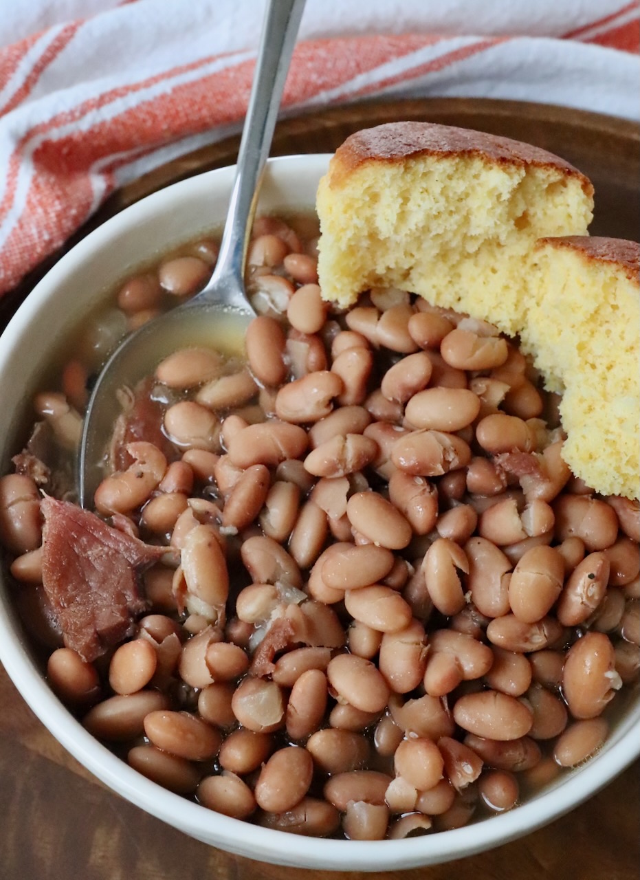 pinto beans in bowl with spoon and cornbread muffin on the side