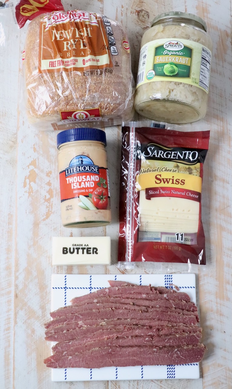 ingredients for reuben sandwich on white wood board