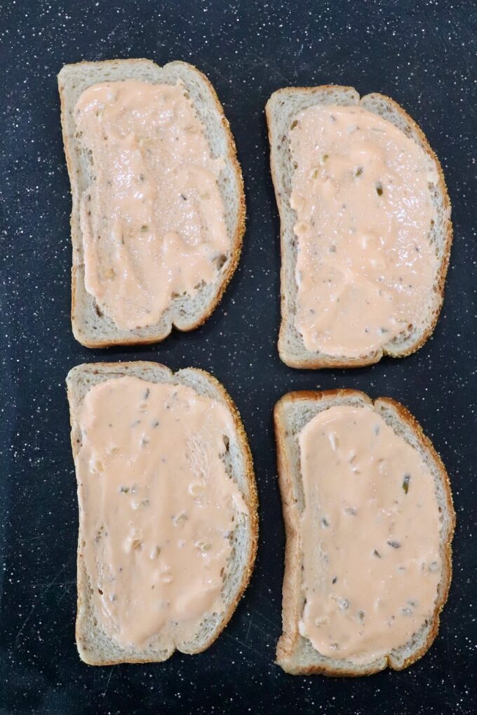 pieces of bread with Thousand Island dressing spread on the bread, on a cutting board