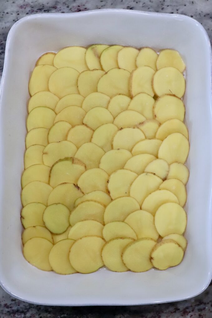 thinly sliced potatoes in baking dish