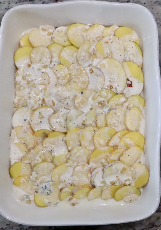 thinly sliced potatoes in baking dish covered with a creamy sauce