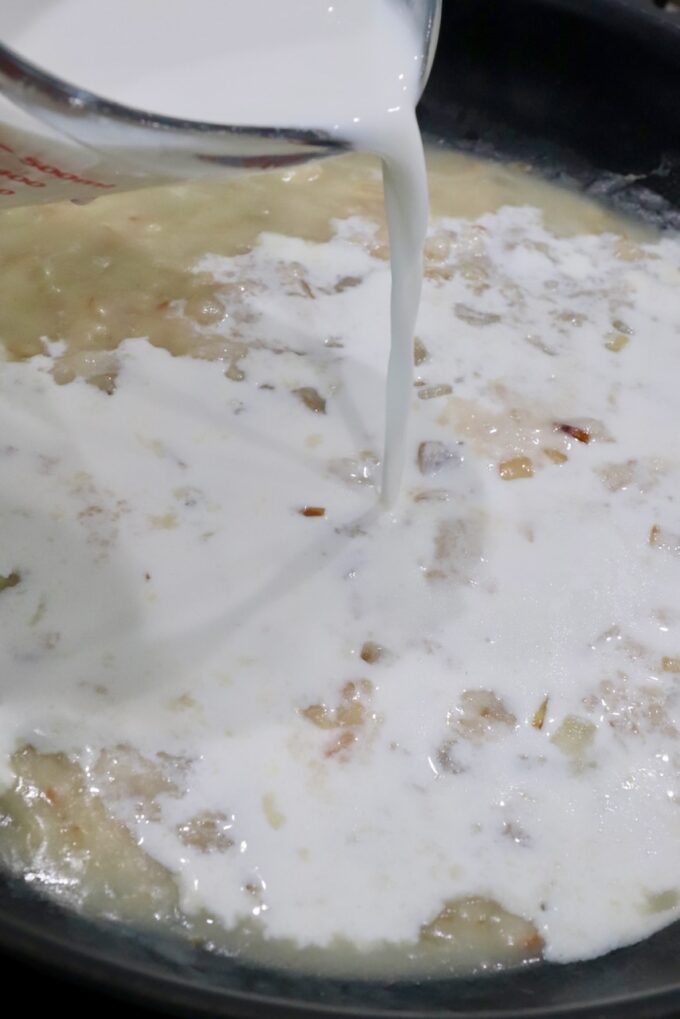 milk poured into a skillet with a roux and cooked onions