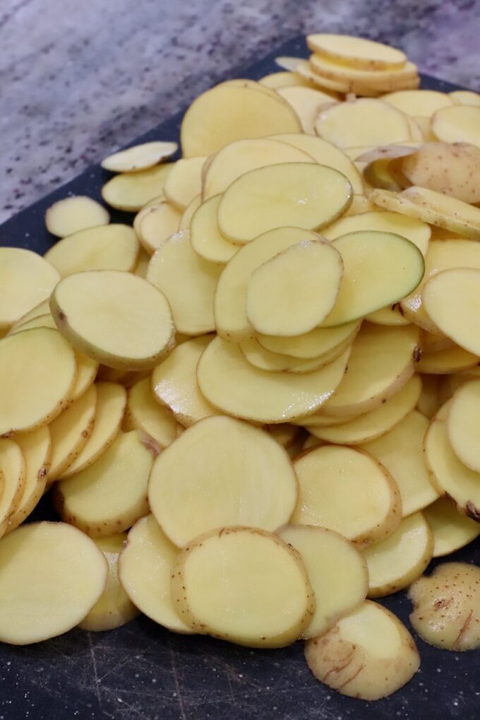 thinly sliced gold potatoes on cutting board
