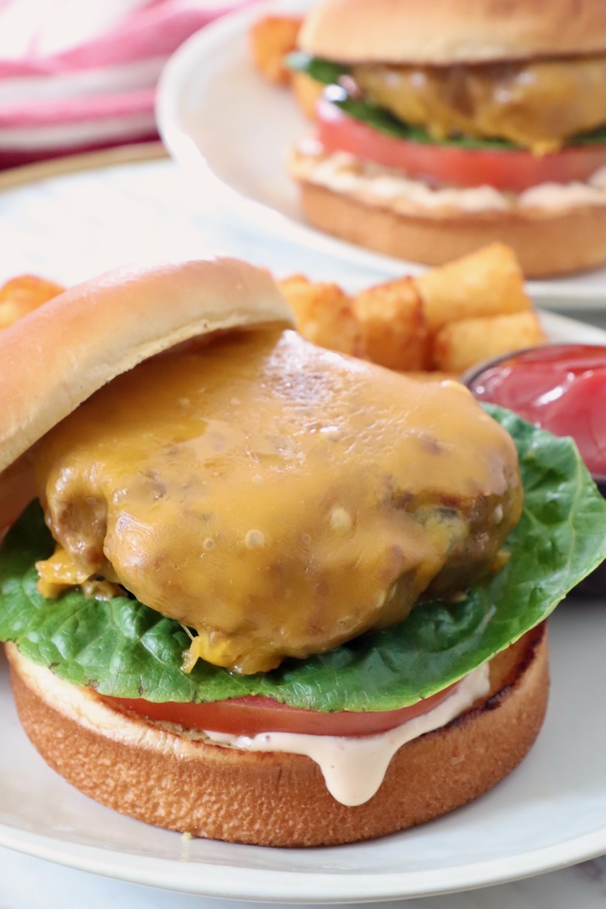 cheeseburger on bun with lettuce, tomato and burger sauce