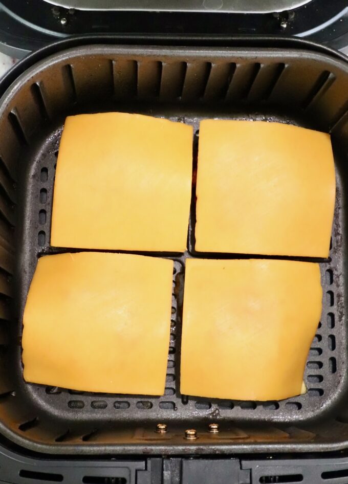 cooked burger patties topped with slices of cheese in air fryer