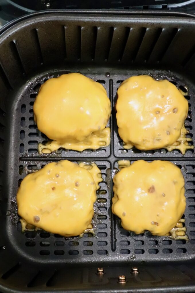 cooked burger patties topped with melted cheese in air fryer