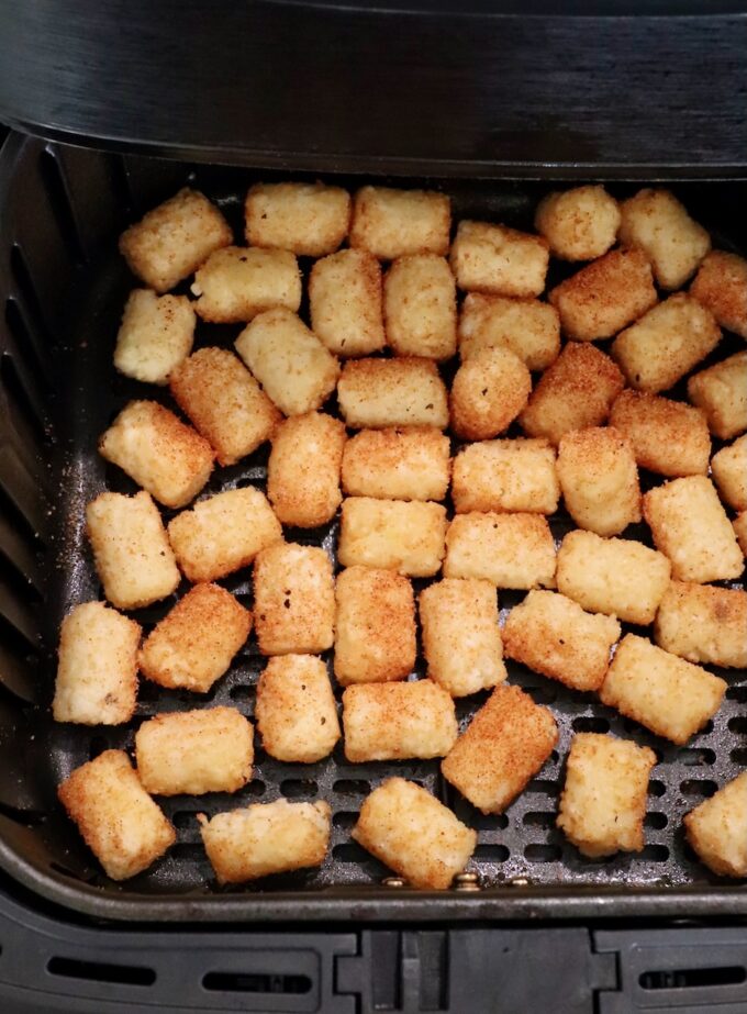 cooked seasoned tater tots in an air fryer basket