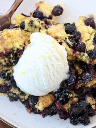 blueberry dump cake on plate with fork and scoop of ice cream on top
