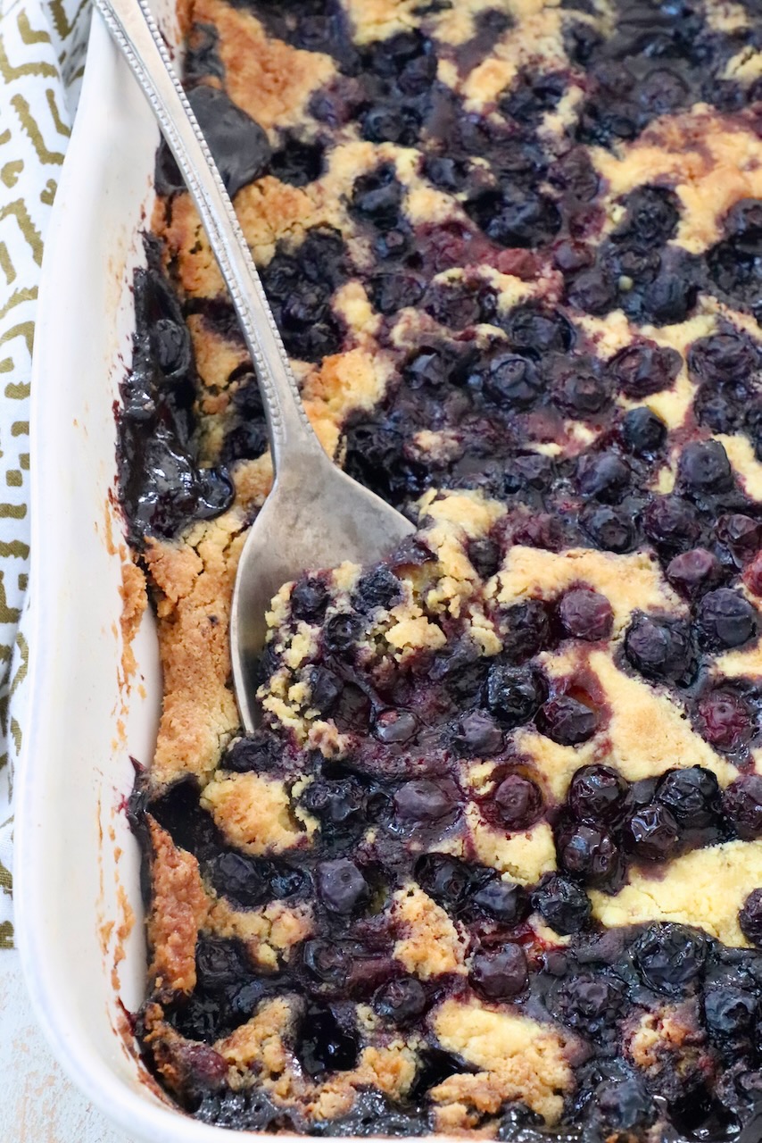 blueberry dump cake in baking dish with serving spoon