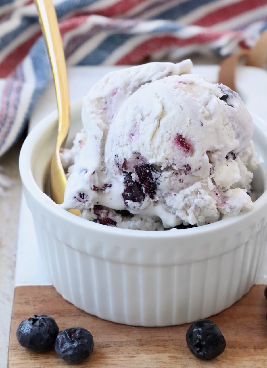 scoops of blueberry ice cream in a small bowl with a gold spoon