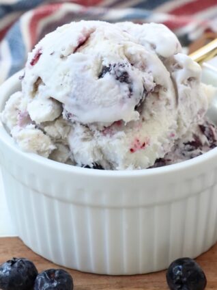 scoops of blueberry ice cream in small bowl with gold spoon