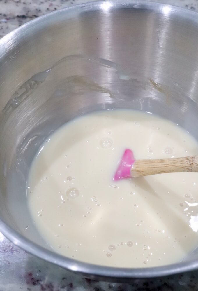 sweetened condensed milk and vanilla mixed together in a bowl with a small spatula