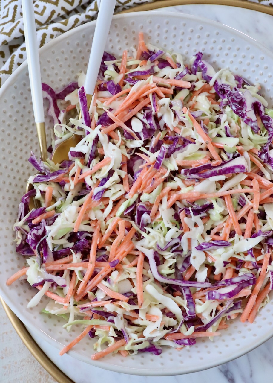 prepared coleslaw in large bowl with spoons