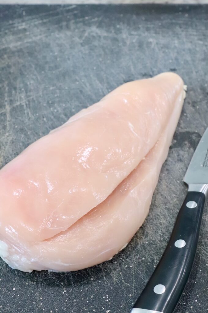 chicken breast sliced in the middle on cutting board