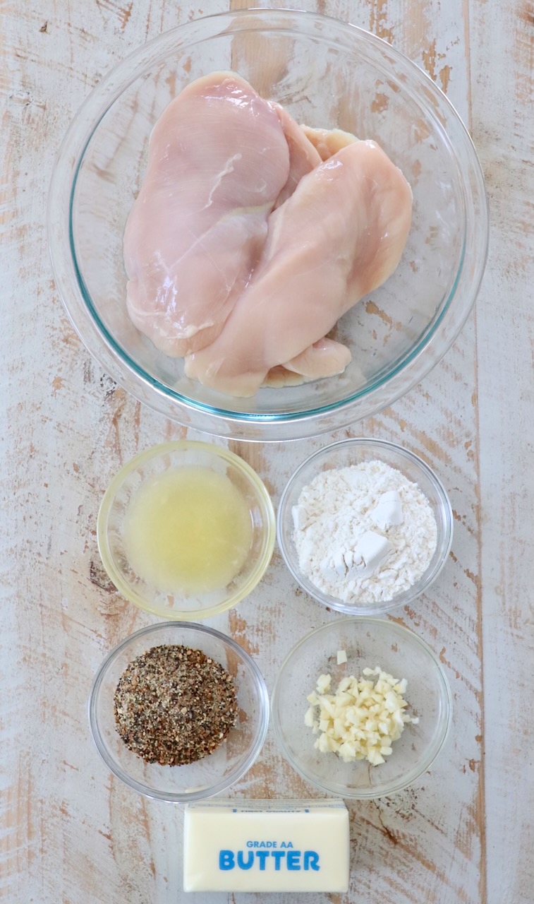 ingredients for lemon pepper chicken on white wood board