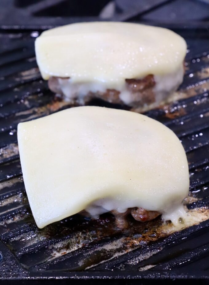 cheese topped burger patties on grill pan