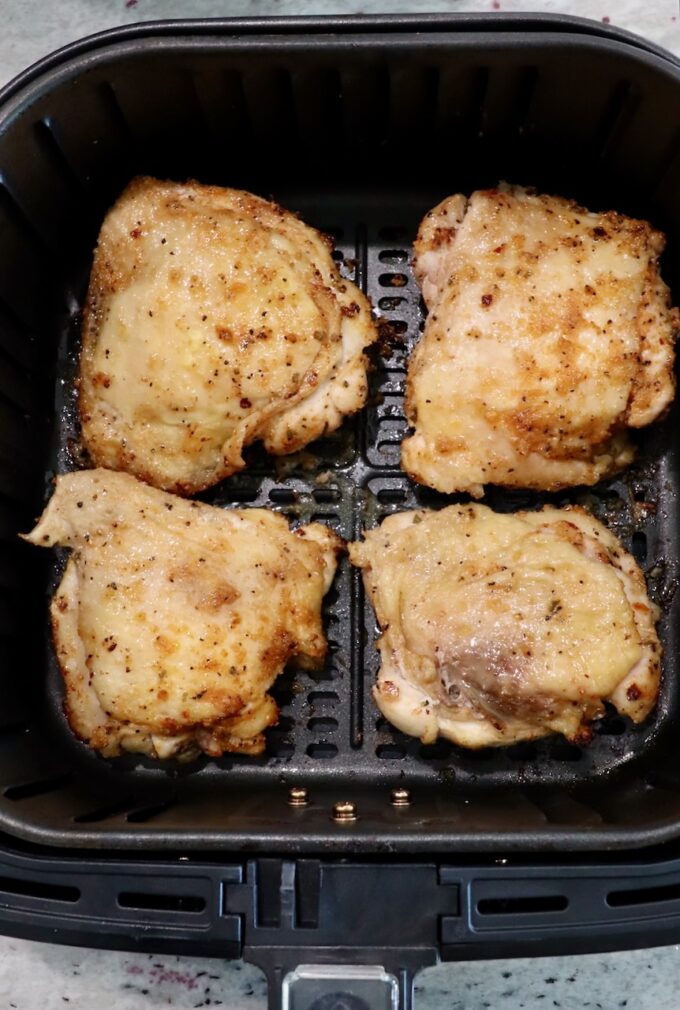 partially cooked bone-in chicken thighs in air fryer basket