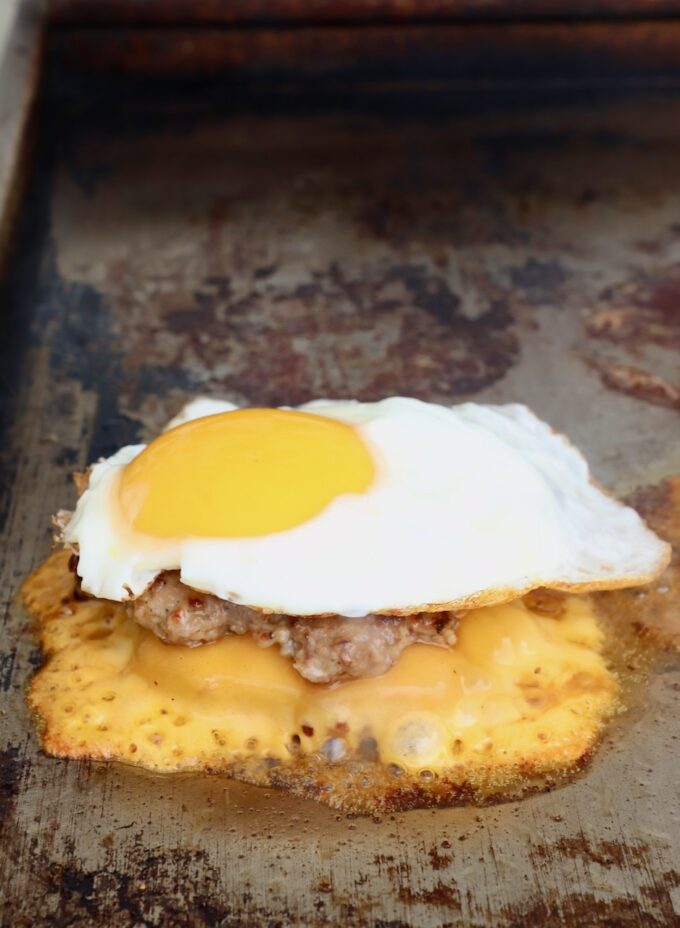 fried egg on top of smashed burger on flat top