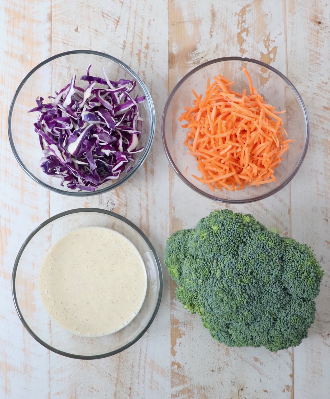 ingredients for broccoli slaw on white wood board