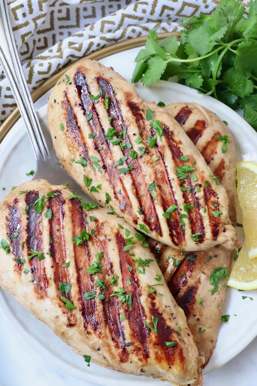 grilled chicken breasts on plate with lemon wedges