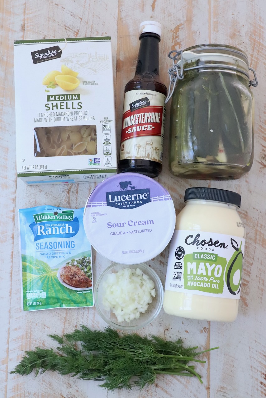 ingredients for dill pickle pasta salad on white wood board