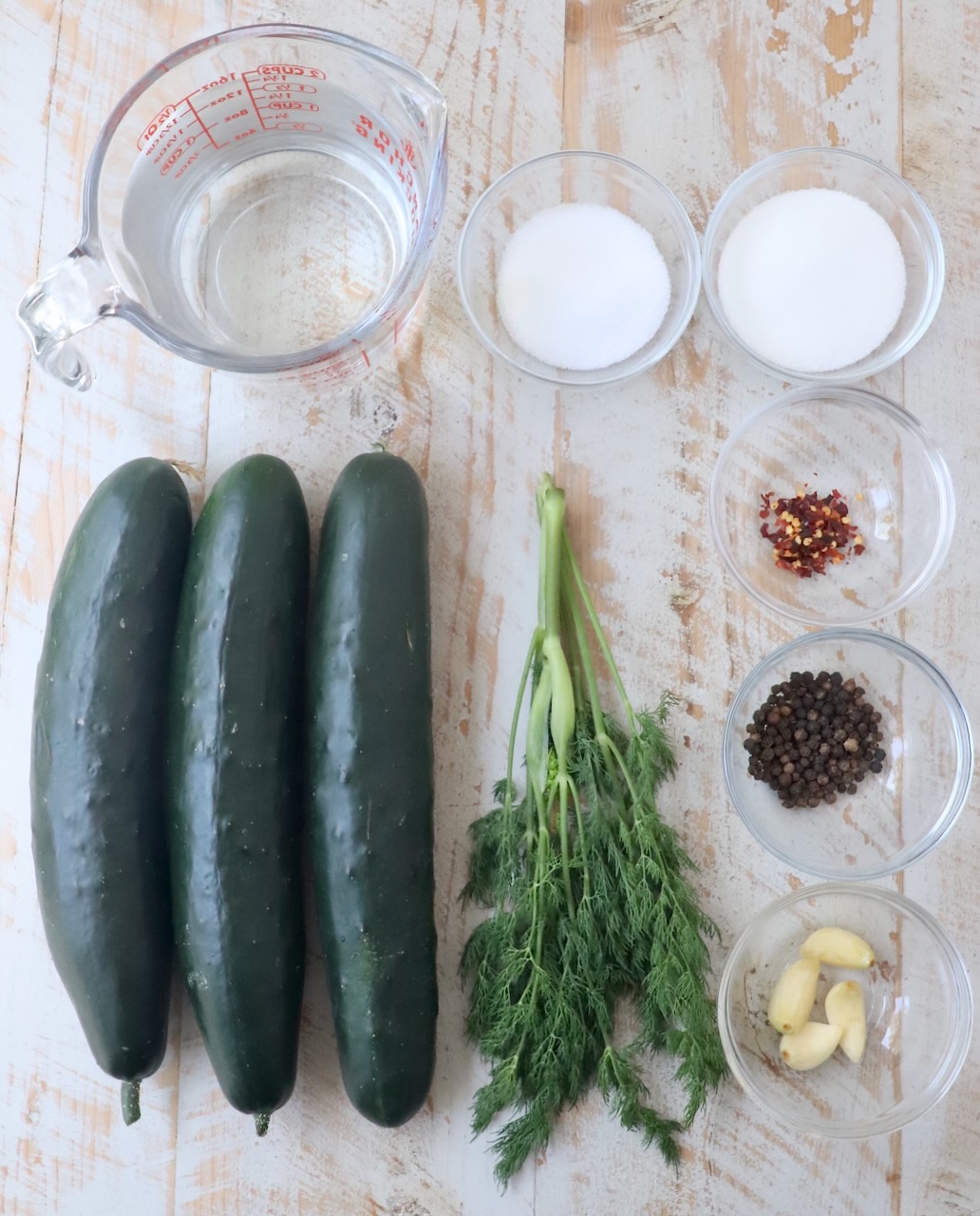 ingredients for homemade pickles on white wood board