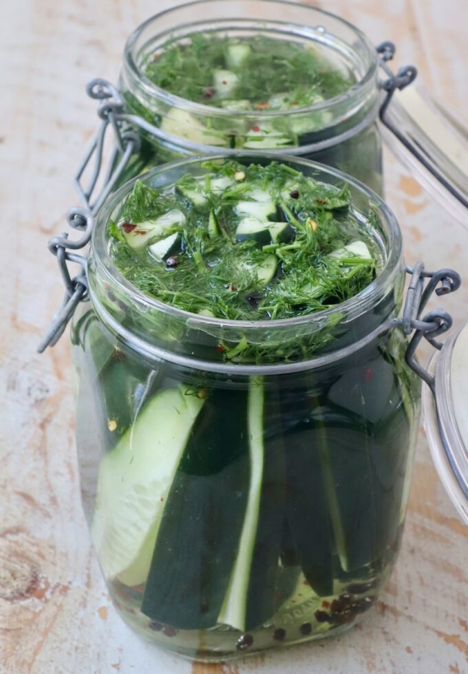 cucumber spears in glass jars with fresh dill, garlic and brining liquid