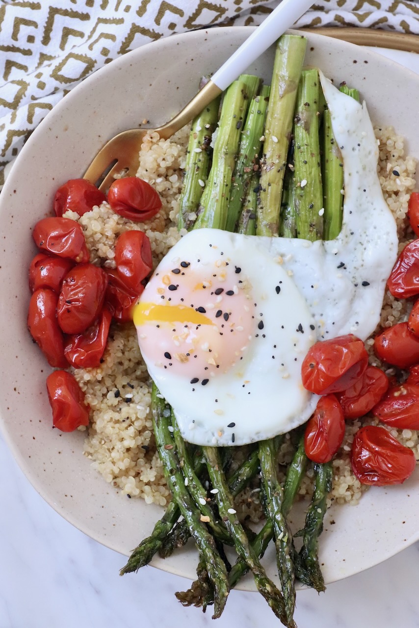cooked asparagus in bowl with roasted tomatoes, quinoa and a fried egg