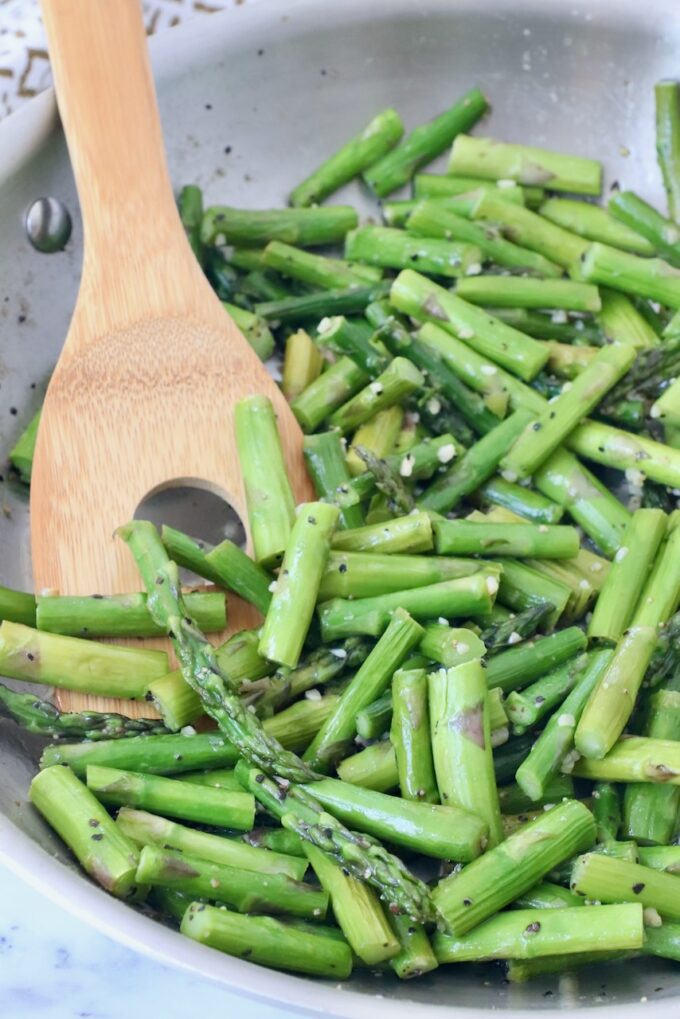 cooked asparagus in skillet with serving spoon