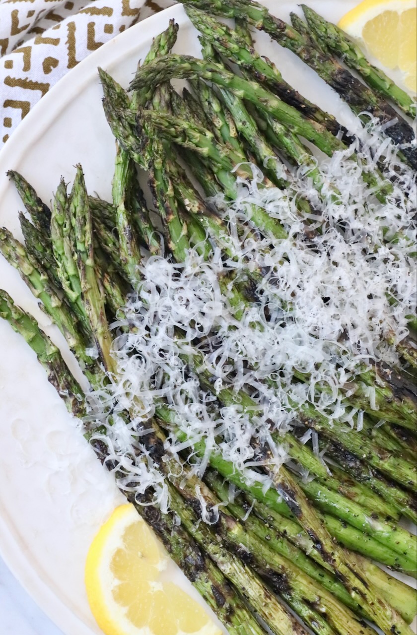 grilled asparagus on plate topped with grated parmesan cheese