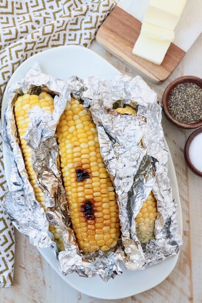 grilled corn on the cob in foil on plate