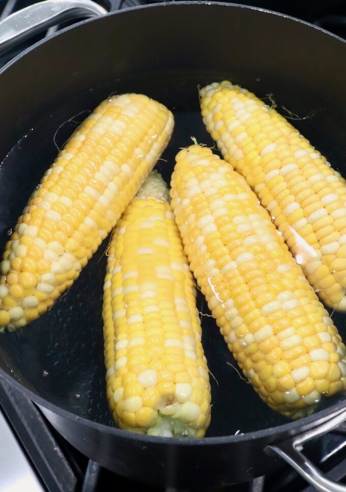 corn cobs in boiling water in pot on the stove