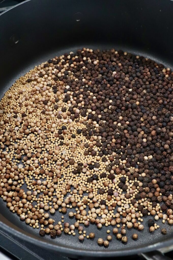 peppercorns, coriander seeds and mustard seeds toasting in skillet