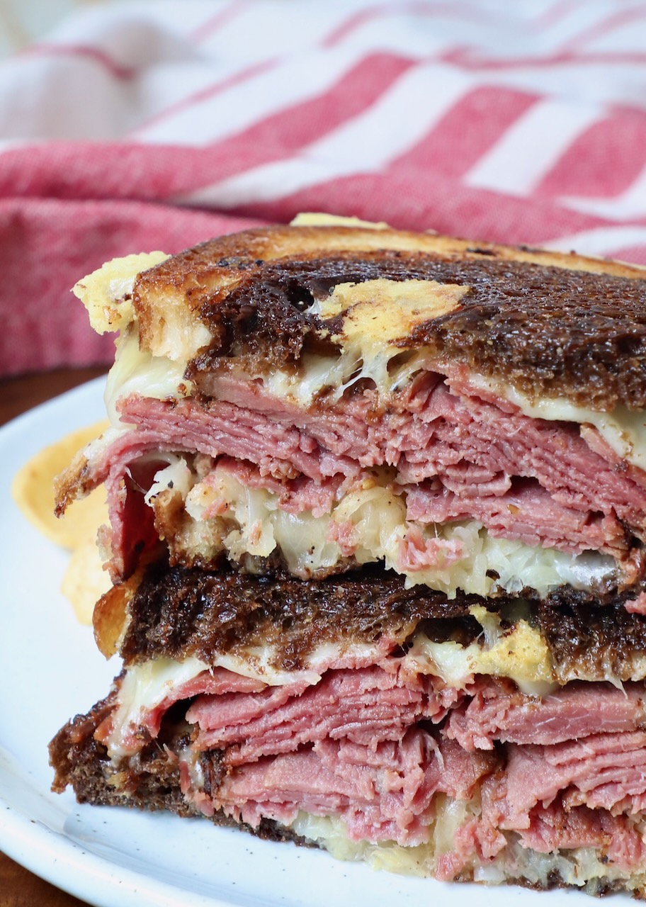 hot pastrami sandwich sliced in half and stacked up on plate
