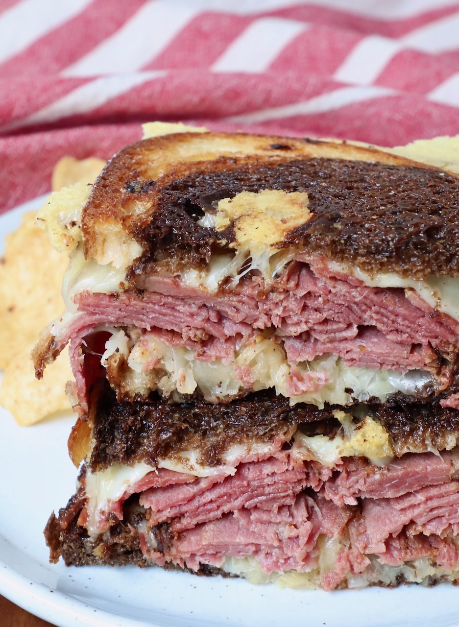 hot pastrami sandwich sliced in half and stacked up on a plate