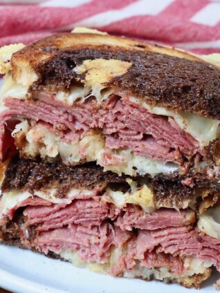 pastrami reuben sandwich cut in half and stacked up on plate