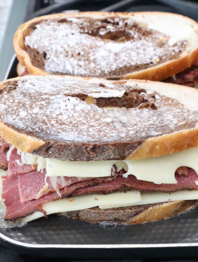 uncooked pastrami reuben sandwiches on griddle