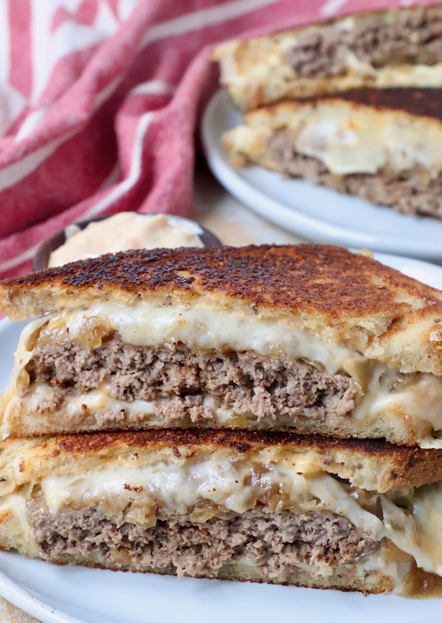 patty melt sandwich cut in half stacked up on each other on plate