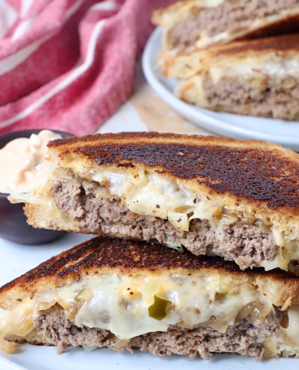 patty melt sliced in half and stacked up on a plate
