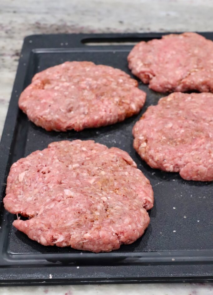 seasoned uncooked burger patties on cutting board