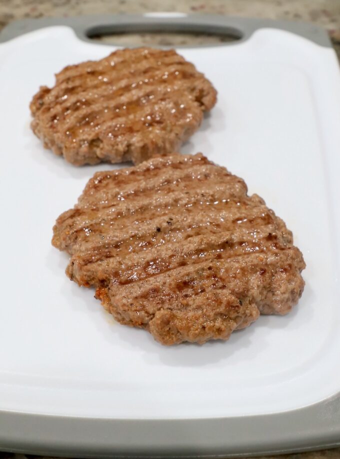 cooked burger patties on cutting board