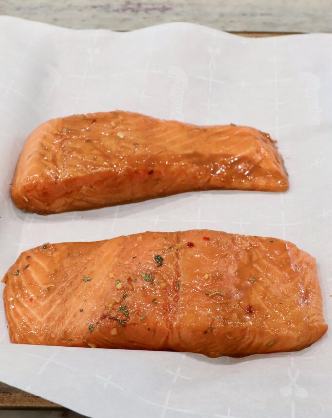 marinated pieces of salmon on parchment-lined baking sheet